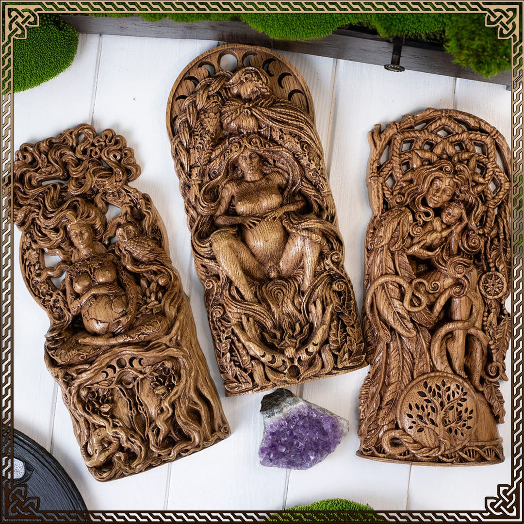 Wiccan god and goddess statues placed on a wooden deity altar with candles and herbs.