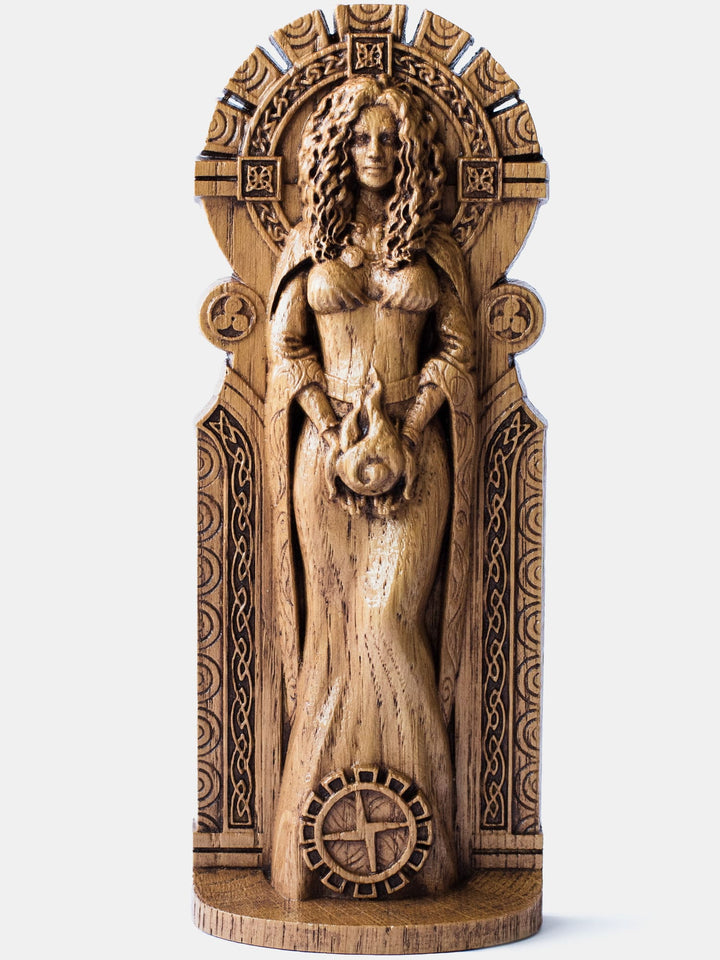 Brigid the Flame oak figurine depicting the Celtic goddess holding fire in her hands with a Brigid's cross at her feet.