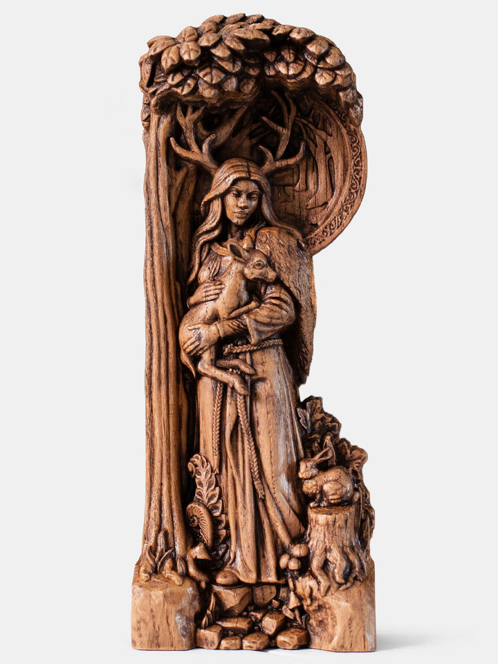 Handcrafted Elen of the Ways horned goddess statue holding a deer on a forest path surrounded by woodland flora