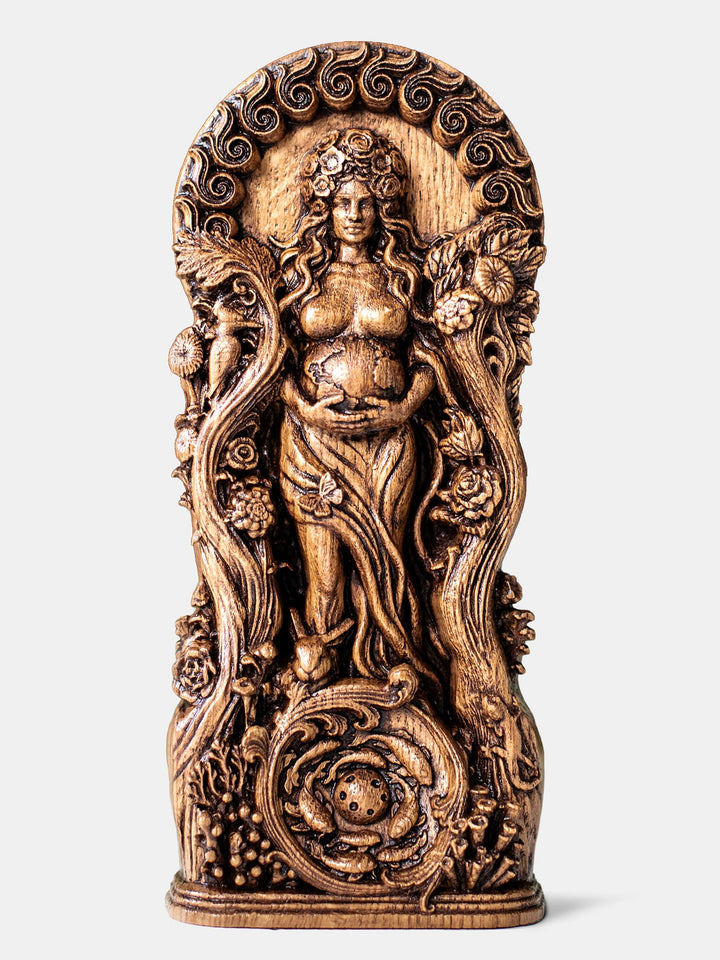 Handcrafted Gaia statue surrounded by botanical ornaments, holding the Earth with sun behind her and moon reflected in water