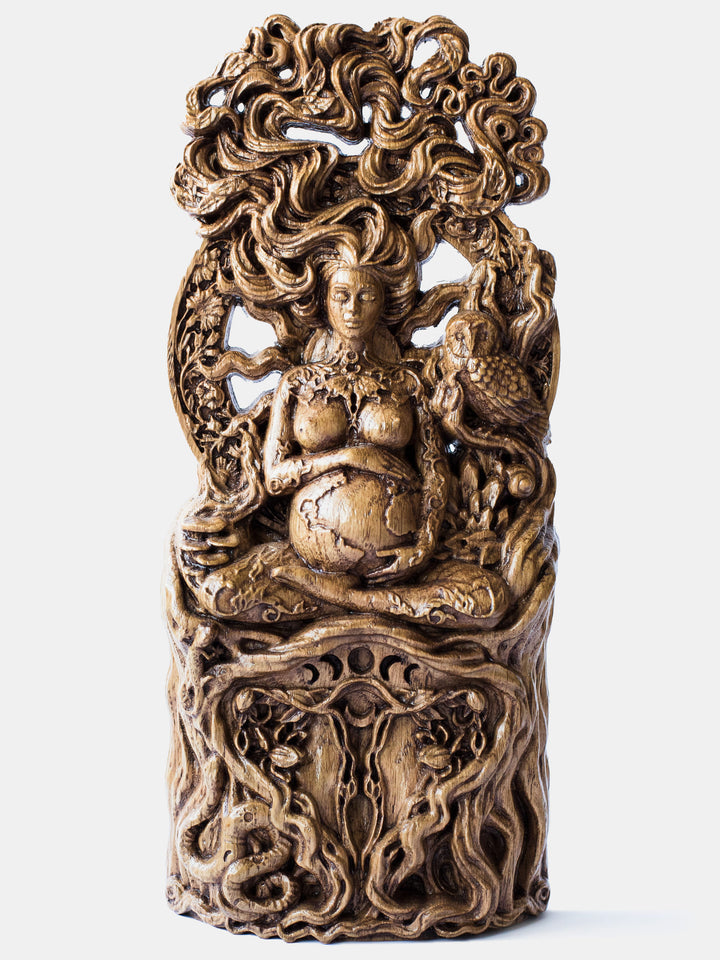 Close-up of the handcrafted oak Gaia statue, showcasing Gaia sitting in a lotus position, embracing Earth with the moon on her shoulders and a butterfly on her chest.