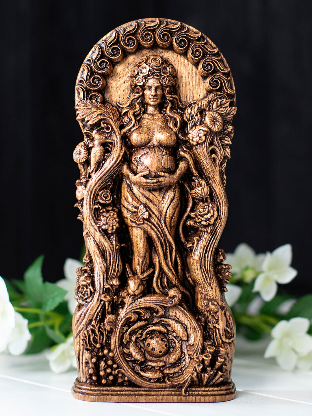 Wooden mother earth statue depicting Gaia with animals, plants, planet Earth, and celestial sun-moon symbolism.