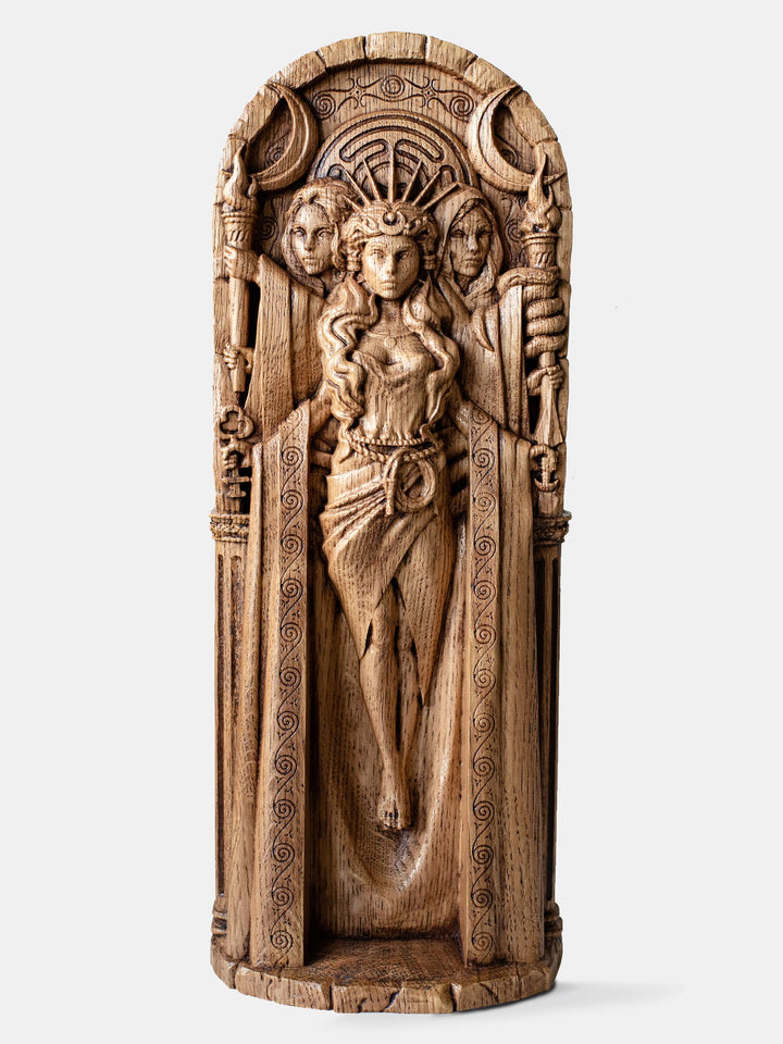Close-up of the handcrafted oak Hecate statue, showcasing three silhouettes against a triple moon with Hecate’s key symbol.