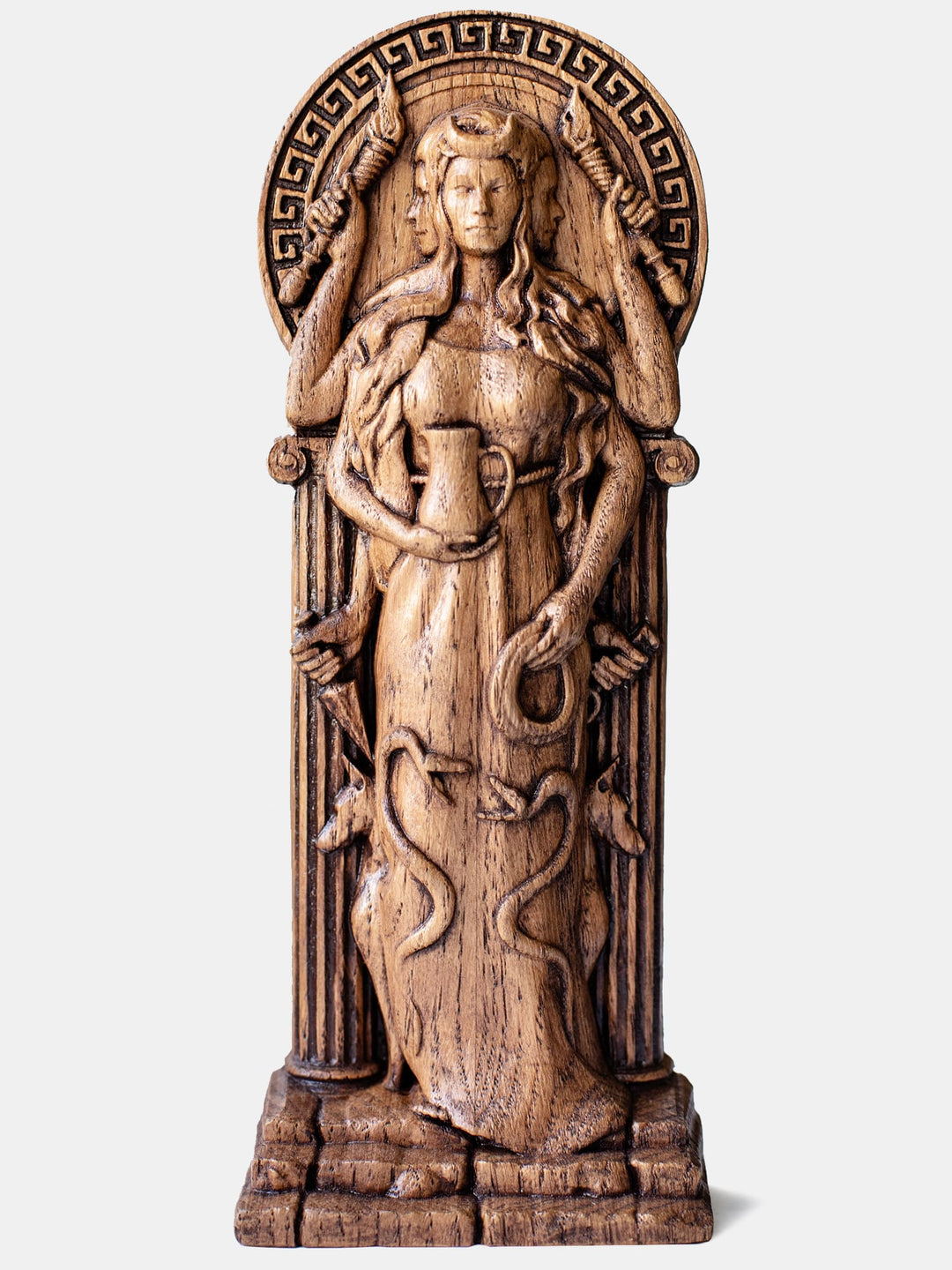 Close-up of the handcrafted oak Hekate statue, showcasing detailed carvings of Hekate with three faces and six hands holding two torches, a lasso, a jug, a ritual dagger, and a key.