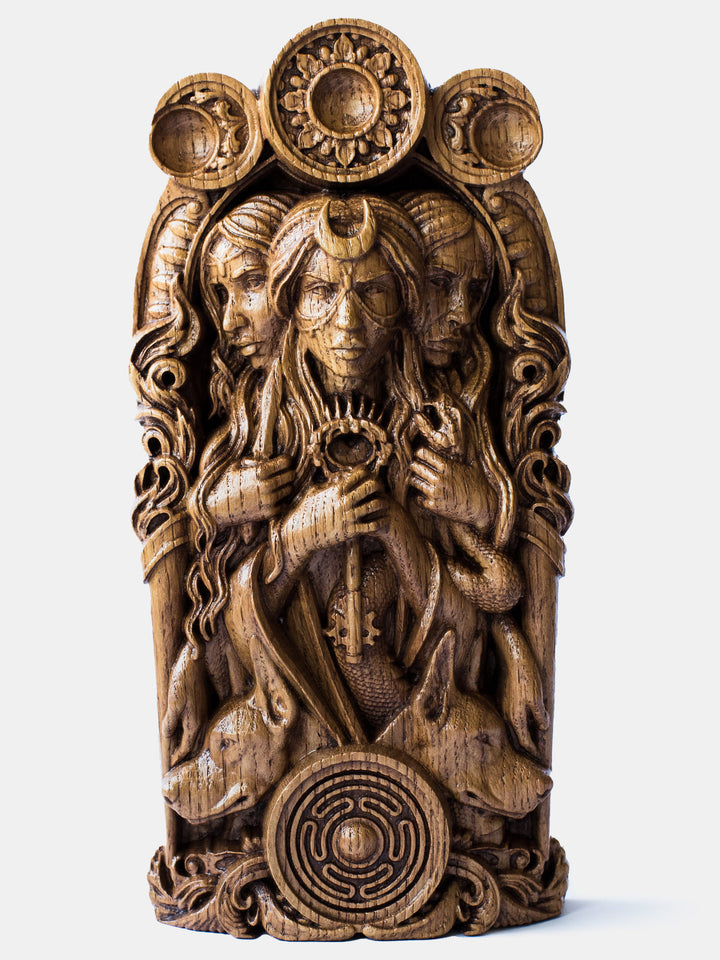 Close-up of the handcrafted oak Hekate bust, showcasing her three faces, key attributes, and the triple moon above her head.