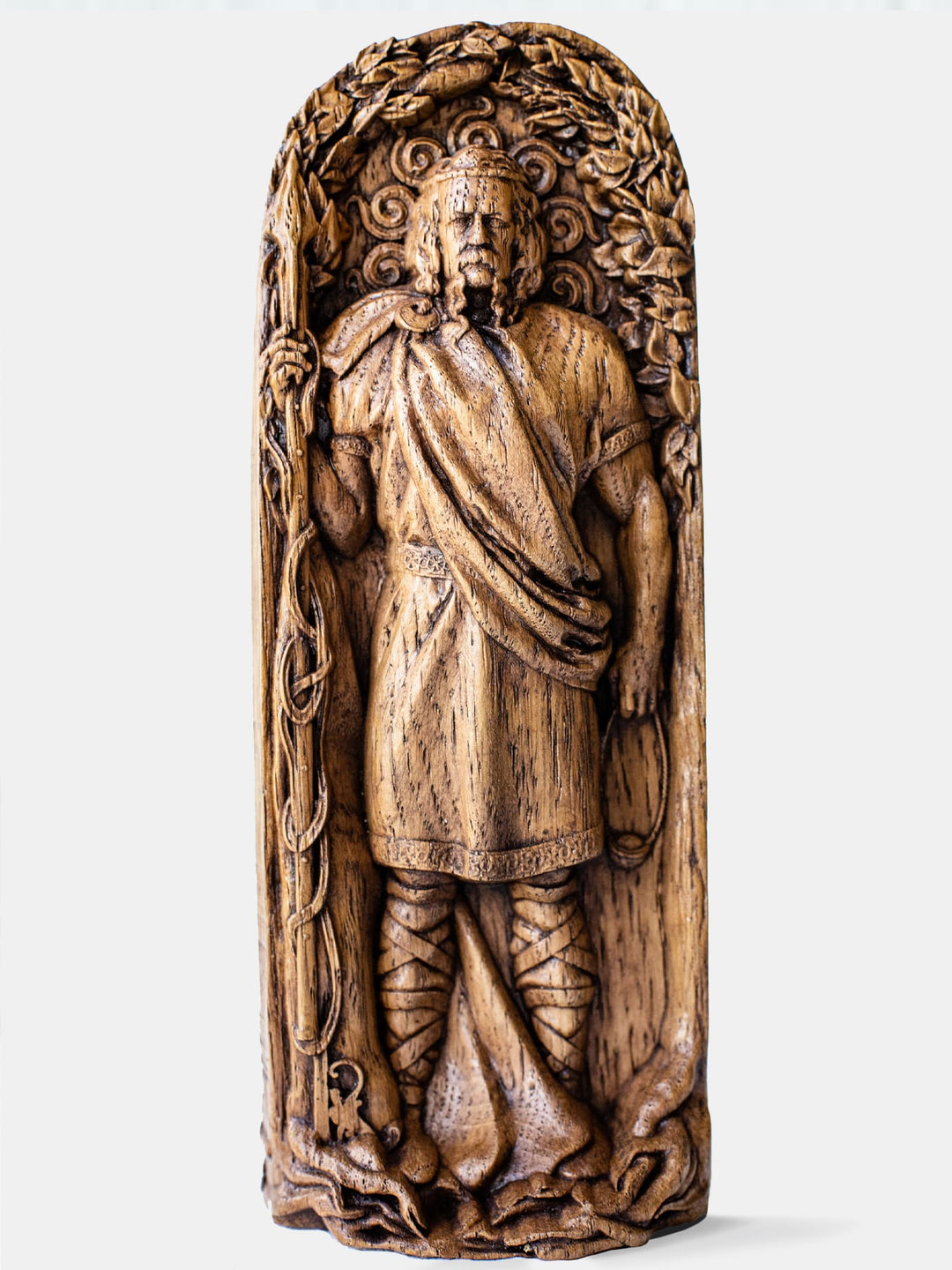 Close-up of the handcrafted oak Lug statue, showcasing the Celtic God with the sun backdrop and a spear in his hand.