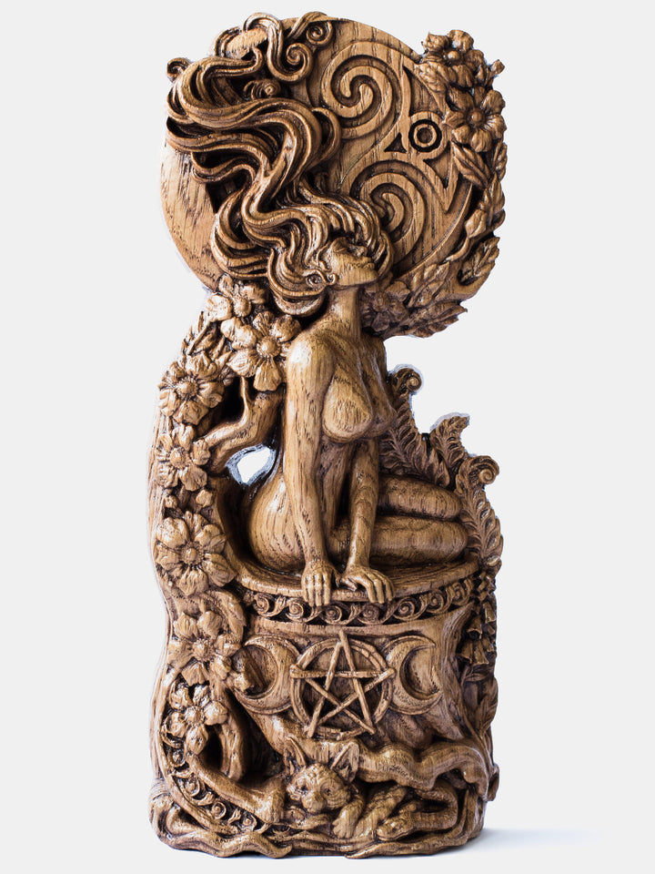 Close-up of the handcrafted oak Moon Goddess statue, showcasing the goddess with a large moon backdrop adorned with flowers, plants, and animals.