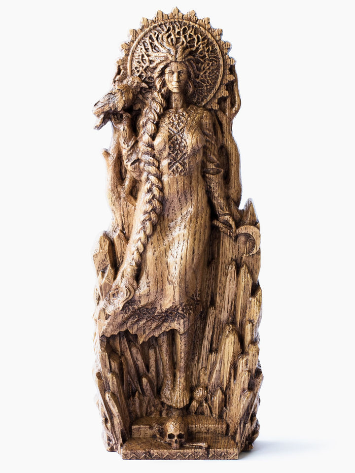 Close-up of the handcrafted oak Morana statue, showcasing the goddess standing on a skull, holding a sickle with a raven on her other hand, and wearing a crown of dry branches.
