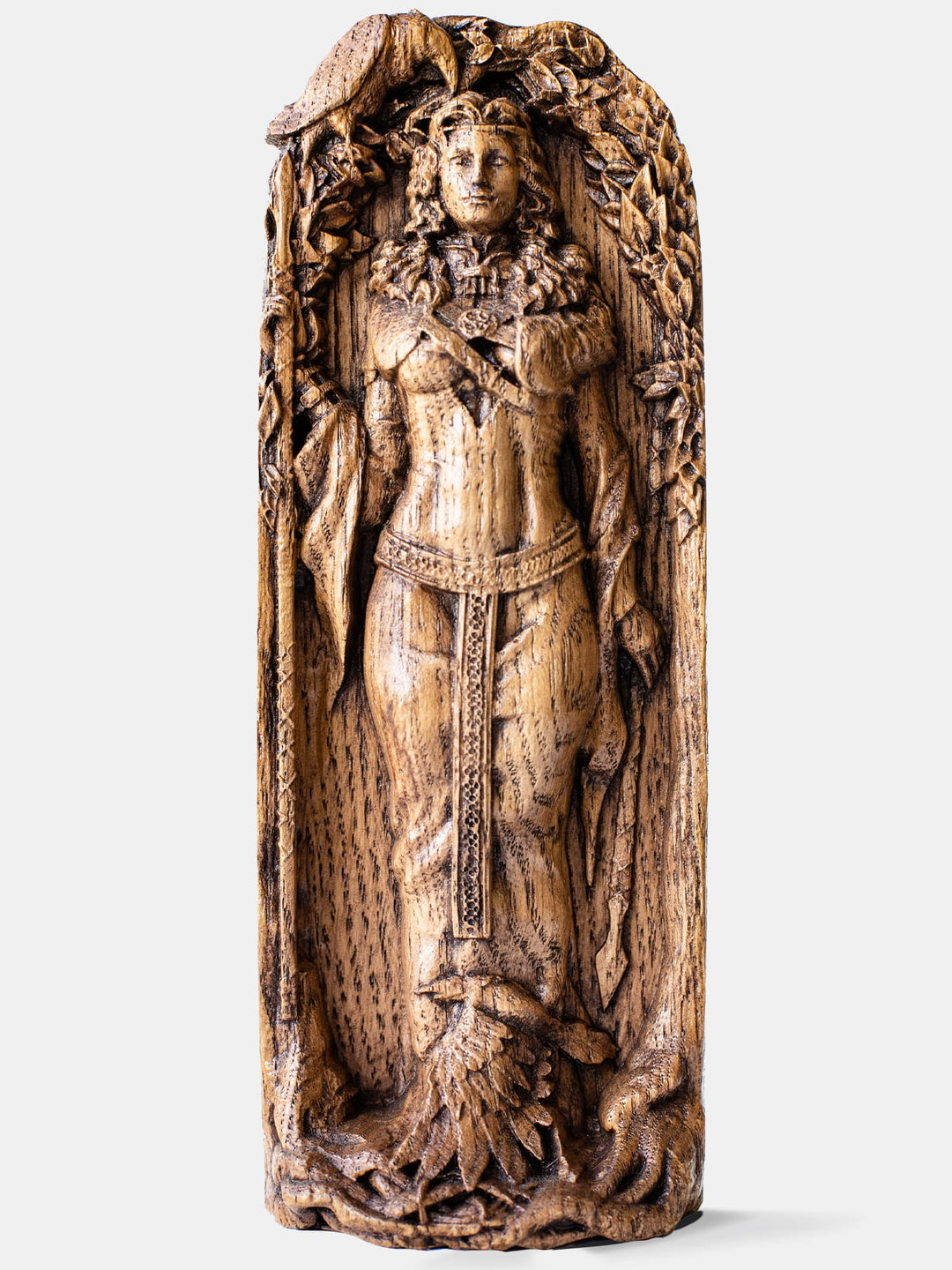 Close-up of the handcrafted oak Morrigan statue, showcasing the goddess holding two spears and standing between trees, accompanied by two ravens.