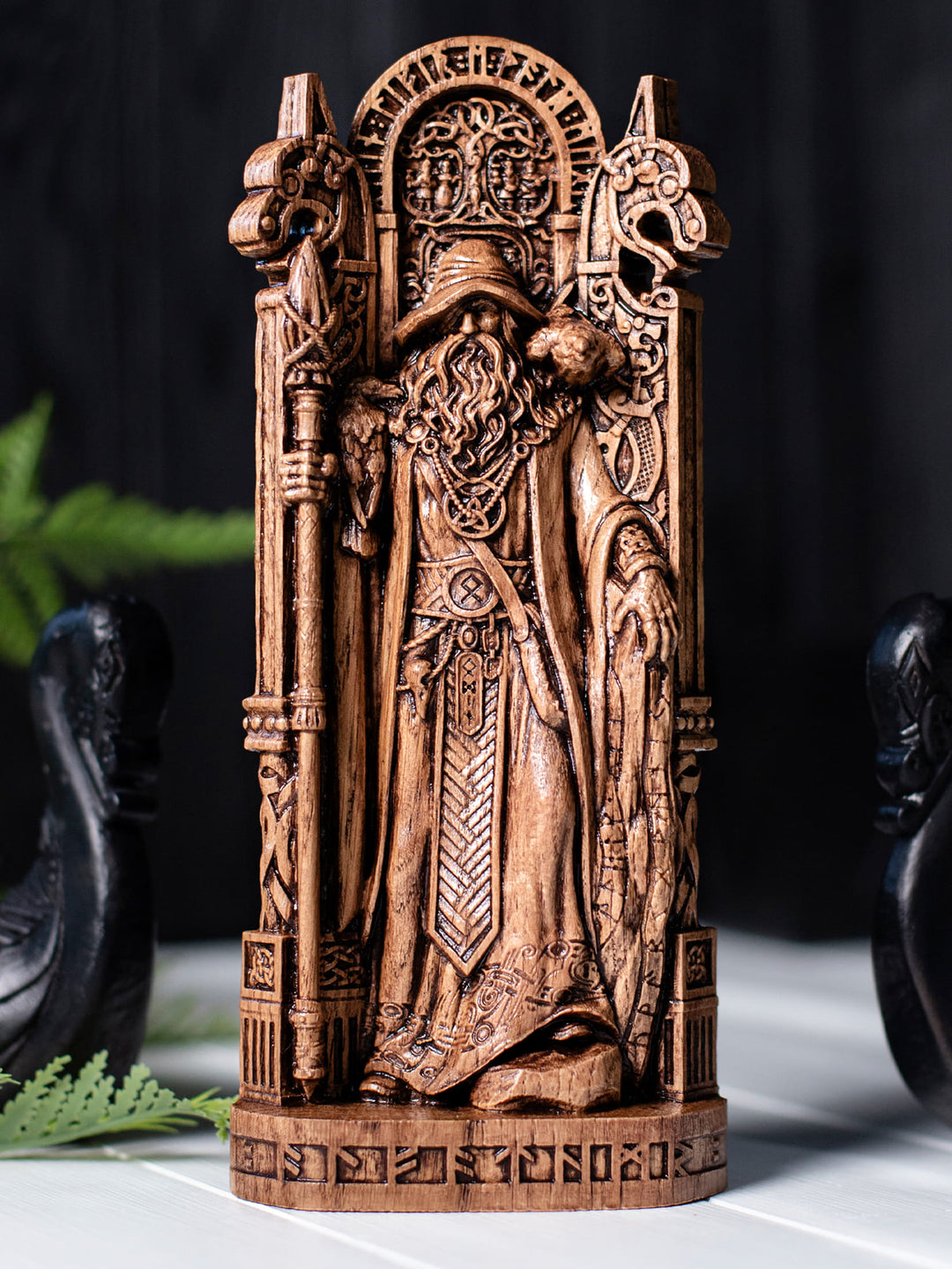 Wooden Odin idol with Yggdrasil, runic inscription, traveler’s cloak, and symbolic Viking-era Norse decor.