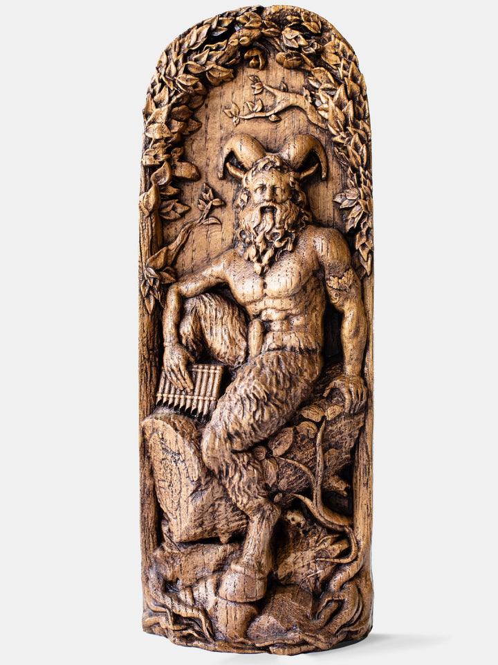 Close-up of the handcrafted oak Pan statue, showcasing the horned god sitting naked on a stump with a musical instrument in his hand.