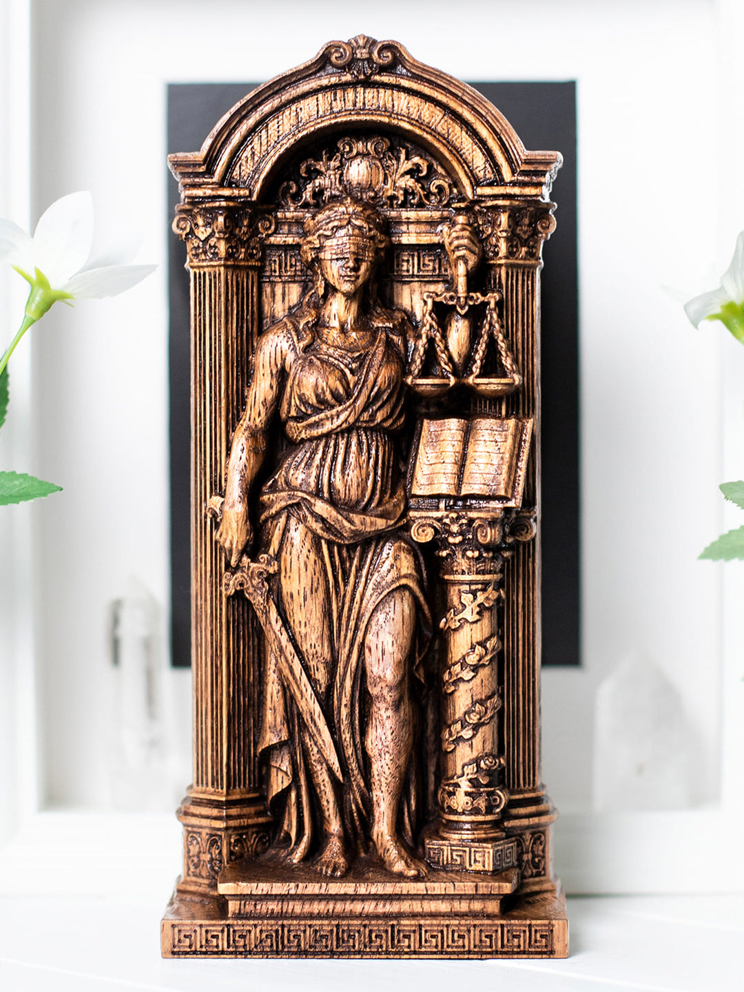 Wooden goddess of justice statue with law book on pedestal, inspired by lady justice and classical Greek sculpture.