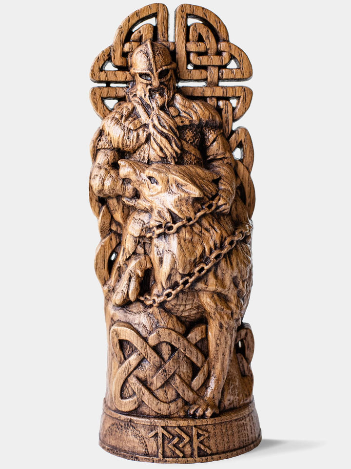 Close-up of the handcrafted oak Týr and Fenrir statue, showcasing Týr placing his hand into Fenrir's mouth while the wolf is being chained.